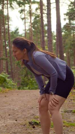 Vertical-Video-Of-Woman-Exercising-Doing-Work-Out-Outdoors-Running-Along-Track-In-Forest-Stopping-For-Breath-Shot-In-Real-Time-1